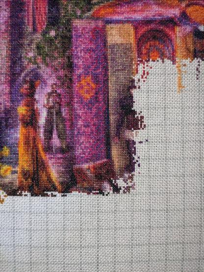 Close up of  a cross stitch piece showing several book spines, a woman in a yellow dress and another humanoid being in the distance holding what appears to be a sword.