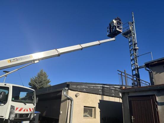 Ein Elektriker fährt mit einer Hebebühne zu einem Mast.