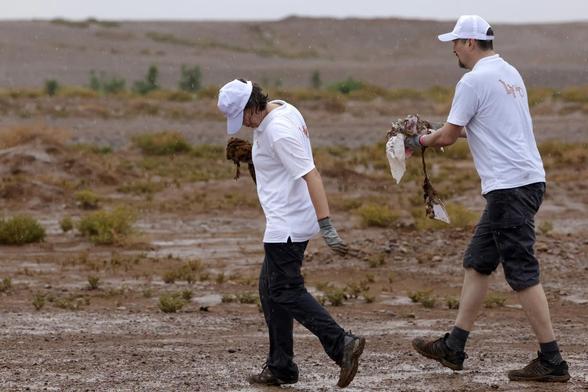 Des bénévoles ramassent des déchets lors d'une campagne de nettoyage de M'Hamid El Ghizlane, aux portes du désert, dans le sud Maroc, le 12 avril 2025.