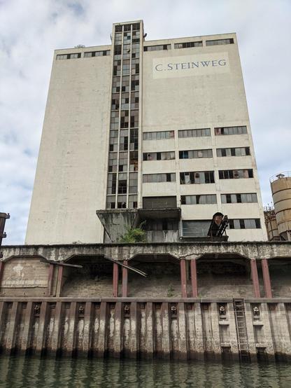 Ein hohes industrielles Gebäude in einer Hafengegend mit der Aufschrift: C. Steinweg