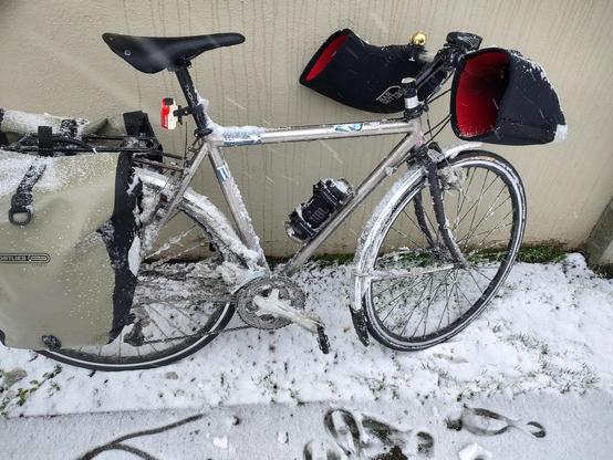 my bike leaning against a wall caked in heavy, wet, dirty snow from riding home in a very rare snow storm