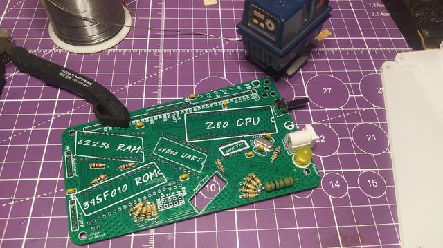 A partially assembled PCB. The PCB is green with a white silkscreen. All the components are placed at jaunty angles. 