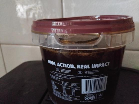Photo of a 1 kilo plastic tub of honey. The lid had been applied such that a vacuum in the container make it very difficult for consumers to remove the lid.