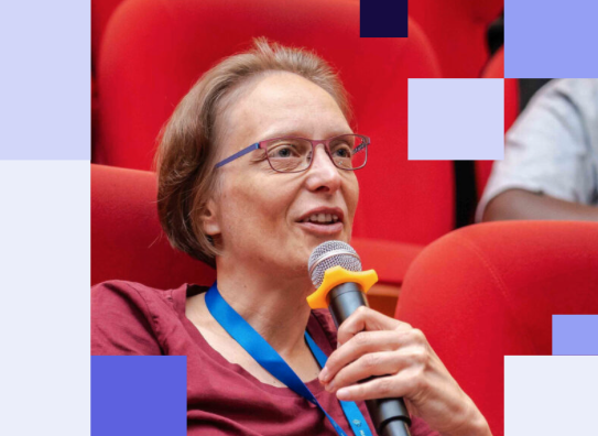 Portrait of Sarah Hoffmann holding a microphone sitting red movie-theater style seating. CC BY-SA 2.0, aratamediasolutions