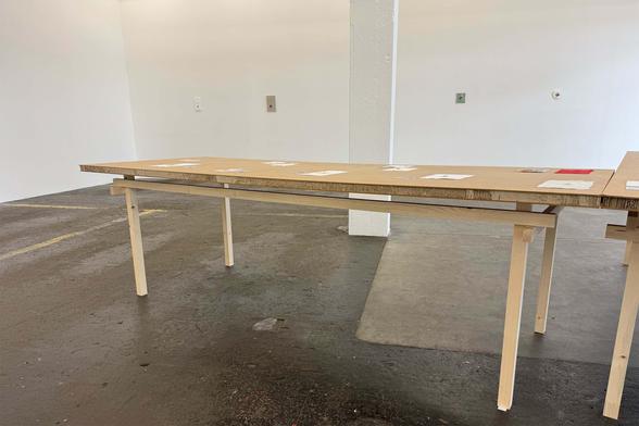 Wide photograph of a minimalist table in a gallery space. 