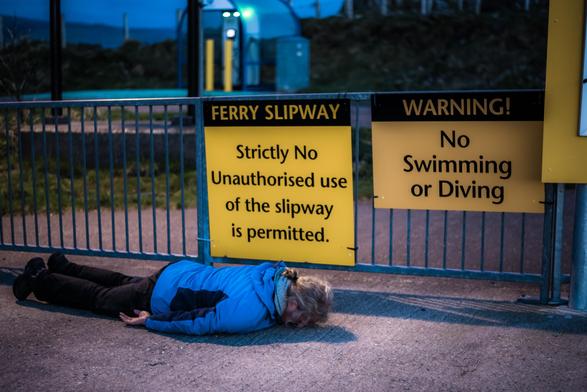 Eine Person liegt vor dem Schild "Strictly no  unauthorised use " bäuchlings auf dem Boden (Planking). 