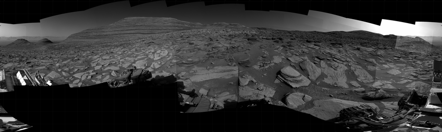 A black and white mosaic capturing a Martian landscape. In detail, NASA's Mars rover Curiosity took 31 images in Gale Crater using its mast-mounted Right Navigation Camera (Navcam) to create this mosaic. The seam-corrected mosaic provides a 360-degree cylindrical projection panorama of the Martian surface centered at 167 degrees azimuth (measured clockwise from north). Curiosity took the images on April 20, 2025, Sol 4516 of the Mars Science Laboratory mission at drive 1458, site number 115. The local mean solar time for the image exposures was from 2 PM to 3 PM. Each Navcam image has a 45 degree field of view.