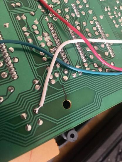 A close-up of the underside of the R/P PCB of a Tascam 424mkII multitrack cassette recorder, where four jumper wires (red, white, blue and yellow) have been installed to bridge a crack. The location of the crack has been noted with a line from a Sharpie marker.