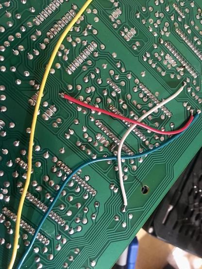 A close-up of the underside of the R/P PCB of a Tascam 424mkII multitrack cassette recorder, where four jumper wires (red, white, blue and yellow) have been installed to bridge a crack. The location of the crack has been noted with a line from a Sharpie marker.