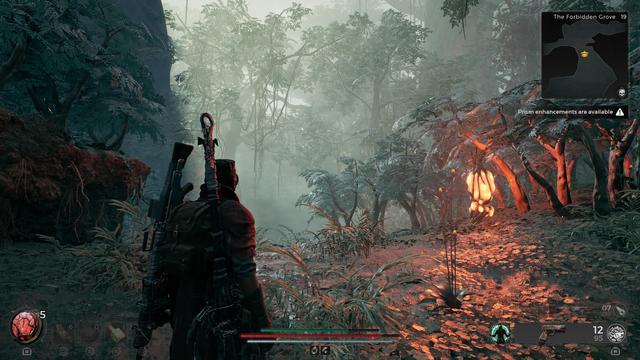Figure carrying a large blade & gun standing in a misty forest, partially lit by an orange lantern plant.