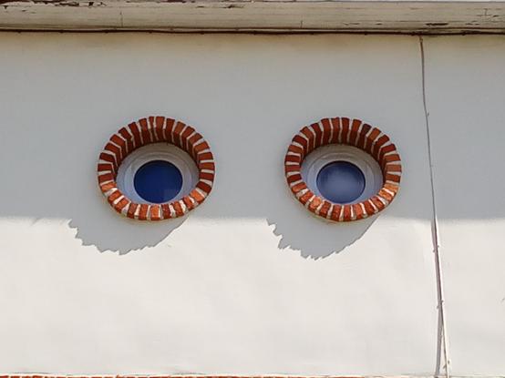 Weiße Fassade mit zwei Ochsenaugen - das Haus hat Augen.