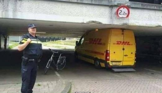 Gelbes DHL-Paketauto, das unter einer 2,2 Meter hohen Brücke stecken geblieben ist