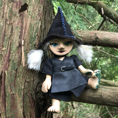 Wooden puppet of a young witch in a tree