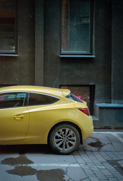 A bright yellow car stands against a dark brown wall. Beautiful contrast. 