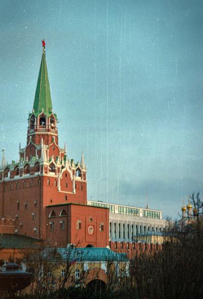 One of the Kremlin's towers in Moscow. The Kremlin's red wall and the golden dome of the temple are visible in the distance. The evening light. There's a lot of dust and scratches in the photo (this is how they gave it away from the camera lab), which I think gives the picture retro charm.