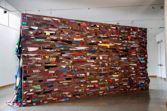 Wall (installation views) by Karyn Olivier, 2017-2018 (clothes, bricks)
A brick wall with various items of clothing squeezed between the horizontal layers.