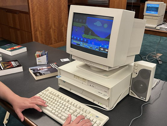 A vintage PC with a person playing Jazz Jackrabbit, a shareware platform game from the early 90s