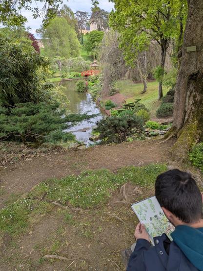 Someone (myself) is painting the landscape figured a river incide a botanic park with a little red chinese bridge.