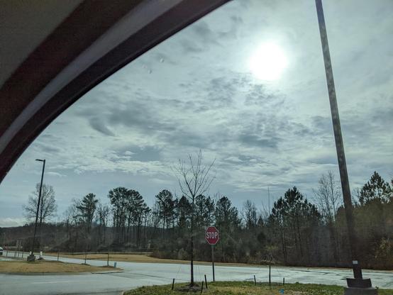 Cloudy sky over stop sign from car. Photo by Dannis Cole.
