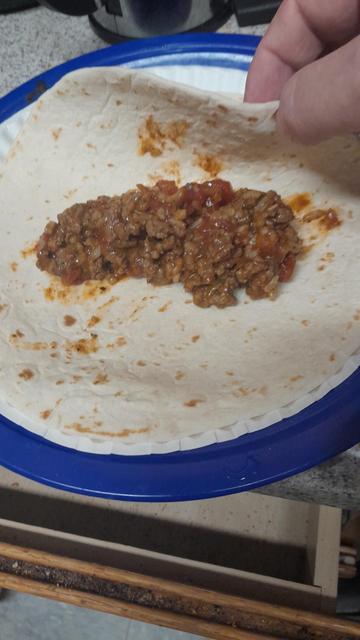 Meat mixture on a tortilla ready for burrito