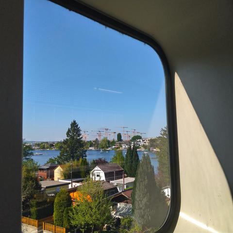 Blick durch ein Fenster der U-Bahn-Station Alte Donau über das Wasser zu einem Feld voller Kräne