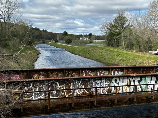 Rusty train bridge with graffiti over a river