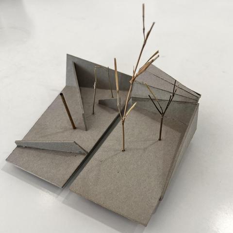 A small  sculpture made of cardboard, two little abstract gardens with shapes and small parts of trees
