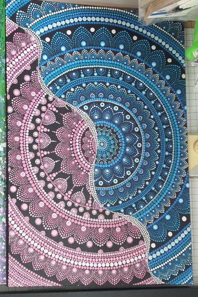 a painting of a mandala design, cropped at the sides, it is blue and pink, one half one color, the other half the other, a wavy line of dots separating the colors