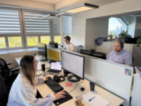 Das Wahl-Team von dev.ORF.at, kurz nachdem die erste Hochrechnung angekommen ist, kontrolliert die Grafiken auf der ORF.at Wahl Seite. Alle drei Personen sitzen an deren Schreibtisch und schauen fokussiert in die Monitore.