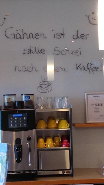 Wandverkleidung hinter der Hotel-Kaffeebar mit der Aufschrift: Gähnen ist der Stille Schrei nach Kaffee.