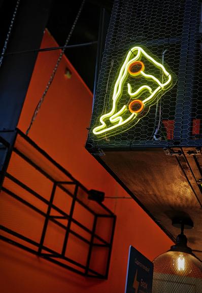 Part of the interior of the cafe. Loft style with a combination of red, black color. The accent is a sign in the form of glowing pizza. 