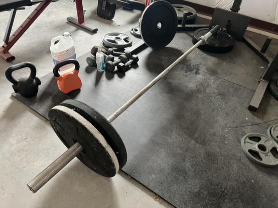 Bar with weights in a landmine attachment on rubber flooring