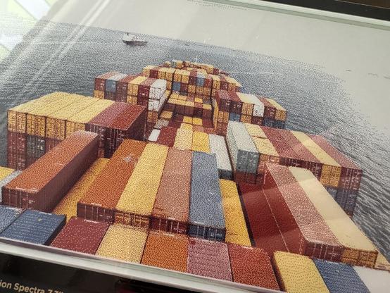 Inky Impression Spectra e-ink display - displaying a sample picture of a ship full of colorful container with the ocean in the background