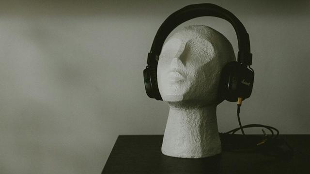 Escultura de piedra de una persona con unos audífonos.