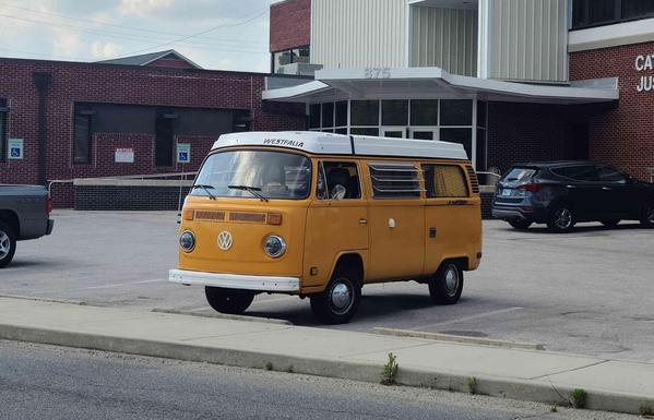 Side view of a yellow Volkswagen van parked in front of a brick Catooosa County Justice Building.