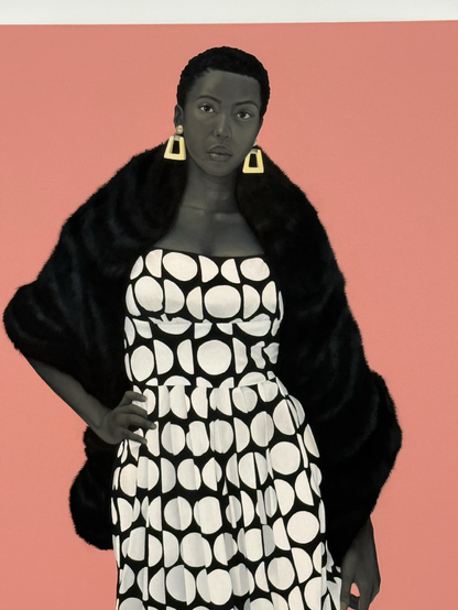A portait by Amy Sherrald—a Black woman in a black-and-white patterned dress regards the viewer. The background is a solid salmon color   