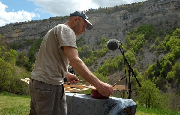 Photo d'un musicien jouant des cordes frappées sur le site des trompes du Faï