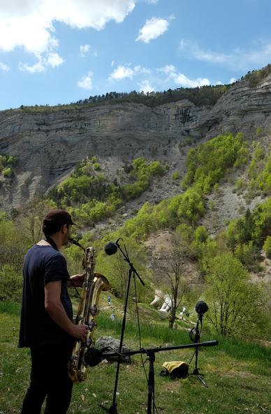Photo d'un musicien jouant du saxophone baryton sur le site des trompes du Faï