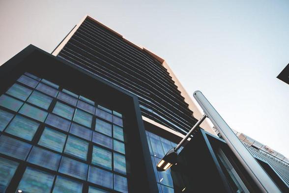 Modern glass office building with skyscraper view from ground up against clear sky