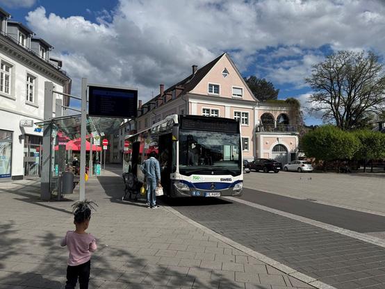 Bus an einer Bushaltestelle, Menschen steigen ein