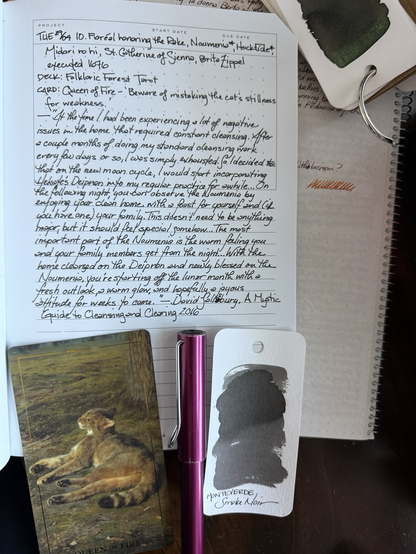 Open notebook with handwritten text from the post at the of the page with additional text: “t the time I had been experiencing a lot of negative issues in the home that required constant cleansing. After a couple months of doing my standard cleansing work every few days or so, I was simply exhausted. So I decided that on the new moon cycle, I would start incorporating Hekate’s Deipnon into my regular practice for a while…On the following night, you can observe the Noumenia by enjoying your clean home with a feast for yourself and (if you have one) your family. This doesn’t need to be anything major, but it should feel special somehow…The most important part of the Noumenia is the warm feeling you and any family members get from the night…With the home cleansed on the Deipnon and newly blessed on the Noumenia, you're starting off the lunar month with a fresh outlook, a warm glow, and hopefully a joyous attitude for the weeks to come.” — David Salisbury, A Mystic Guide to Cleansing & Clearing 2016. Below the text is a card with the painting Wild Cat (1850) by Rosa Bonheur of a wild cat lying on its side in grass. Next to the card is a purple fountain pen and a swatch of gray ink. 