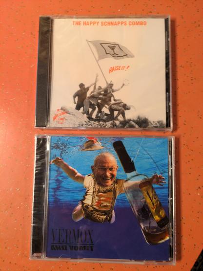 Two, in the shrink wrap polka CDs. On the cover of one, is a reenactment of the Iwo Jima flag raising, but what appears to be the band.  On the flag is a martini glass, and just below the alum's title: Raise It!  The second cover is a parody of Nirvana's Nevermind album cover.  Instead of a baby and money, it is an old polka man and a bottle of Schnapps. The title is: Vermox and Vommit