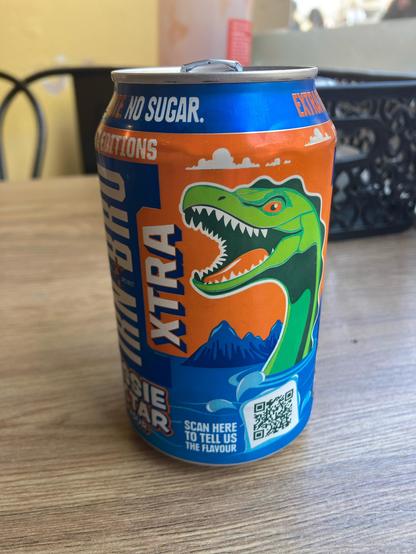 A can of Irn-Bru in its distinctive orange and blue colours, with a bright green dinosaur-like cartoon image of Nessie, the Loch Ness monster