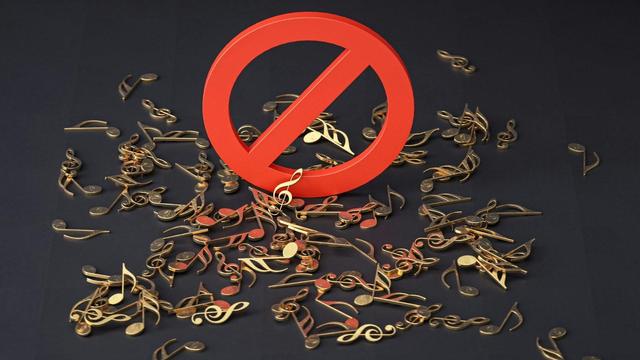 Un icono de prohibdo encima de claves de sol metálicas. Autoría de la imagen: Cdd20 en Unsplash