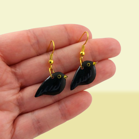 Boucles d'oreilles fantaisie pendantes éco-responsables en forme de petits merles noirs.
Les perles sont réalisées en CD recyclé, découpées et peintes à la main, puis recouvertes de résine époxy.
Les crochets sont en métal doré, mais sont disponibles également dans d'autres métaux et coloris.