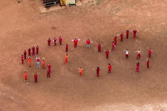 A group of men in the desert spelling out SOS