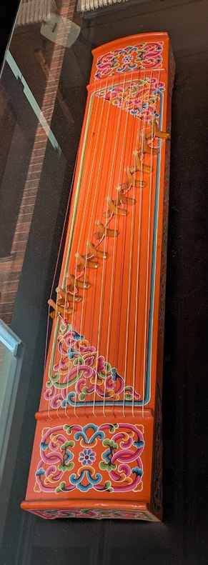 a koto-like instrument from Ruanda, beautifully ornamented with vivid, painted flower motifs