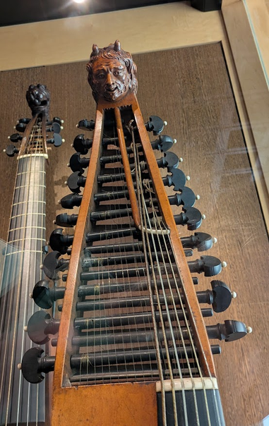a complicated, rare string instrument from old Europe with a beautifully carved head of a male human with tiny devil's horns