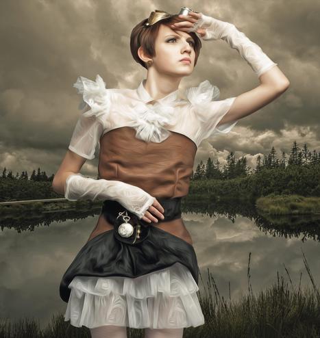 Young woman in steampunk dress and goggles standing in front of a pond.