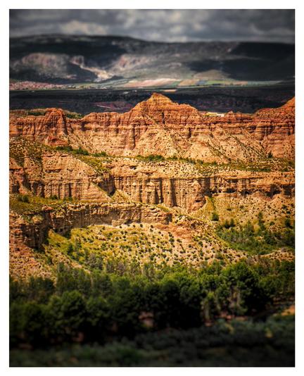 Red mountains in the center of the images with green trees at the bottom and a white landscape behind.